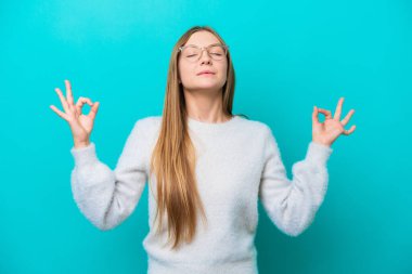 Zen pozisyonunda mavi arka planda izole edilmiş genç Rus kadın.