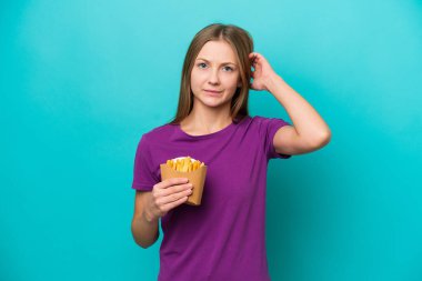 Kızarmış patates yiyen genç Rus kadın mavi arka planda izole edilmiş şüpheleri var.