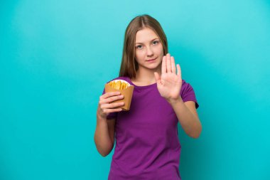 Patates kızartması yakalayan genç Rus kadın mavi arka planda izole edilmiş bir şekilde durup jest yapıyor.