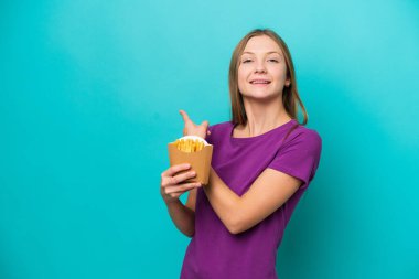 Patates kızartması yakalayan genç Rus kadın mavi arka planda izole edilmiş.
