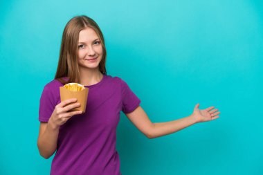 Mavi arka planda izole edilmiş patates kızartması yakalayan genç bir Rus kadını davet etmek için elini yana uzatıyor.
