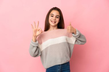 Pembe arka planda izole edilmiş küçük bir kız işaret ve işaret işareti gösteriyor.