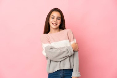 Küçük kız pembe arka planda gülüyor.