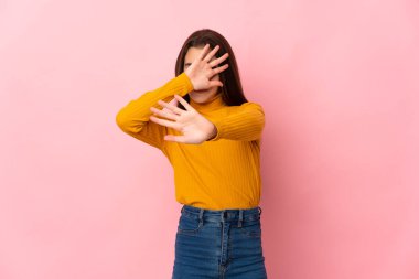 Pembe arka planda izole edilmiş küçük bir kız gergin ellerinizi öne uzatarak