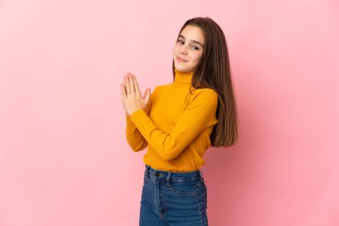 Küçük kız pembe arka planda bir şeyler planlıyor.