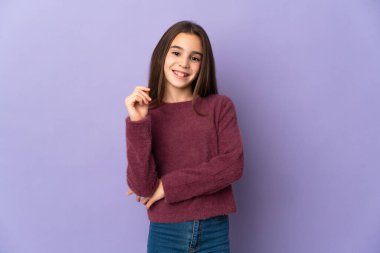 Mor arka planda yalnız küçük kız gülüyor.