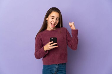 Mor arka planda izole edilmiş küçük bir kız. Telefon zafer pozisyonunda.