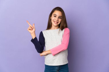 Mor arka planda izole edilmiş küçük kız mutlu ve dik duruyor.