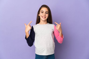 Mor arka planda izole edilmiş küçük bir kız baş parmak işareti yapıyor.