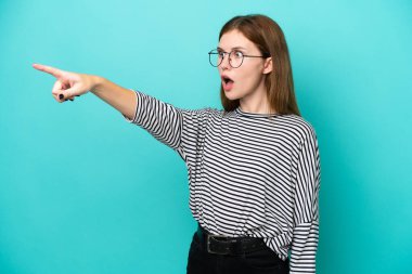 Mavi arka planda izole edilmiş genç bir İngiliz kadın.