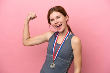 Pembe arka planda madalyalı genç bir İngiliz kadın güçlü bir jest yapıyor.