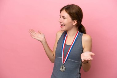 Pembe arka planda madalyaları olan genç bir İngiliz kadın. Şaşırtıcı bir yüz ifadesi var.