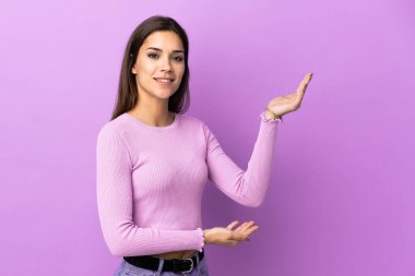 İzole edilmiş arka planda genç beyaz kadın, davet edilmek için ellerini yana uzatıyor.