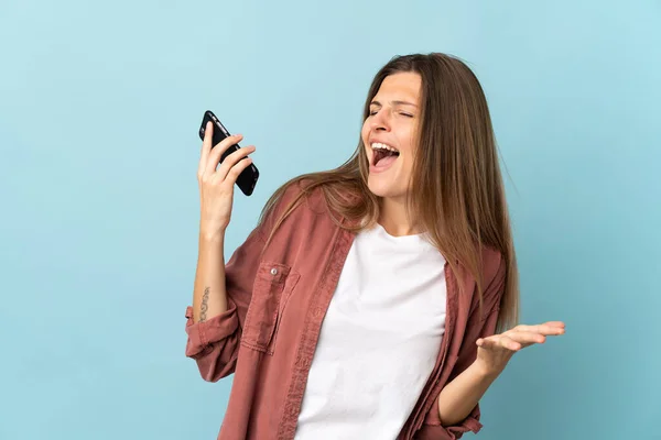 Giovane Donna Slovacca Isolata Sfondo Blu Con Cellulare Canto — Foto Stock