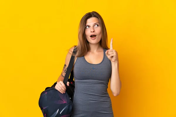 黄色の背景に隔離されたスポーツバッグとスロバキアのスポーツ女性は指を指すアイデアを考えます — ストック写真