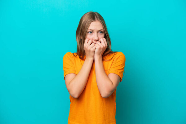 Молодая россиянка, изолированная на синем фоне, нервничает и боится класть руки в рот