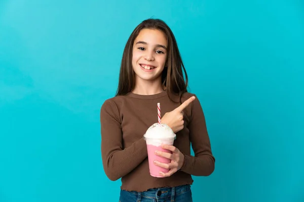イチゴミルクセーキの女の子は 製品を提示する側を指している青の背景に隔離されました — ストック写真