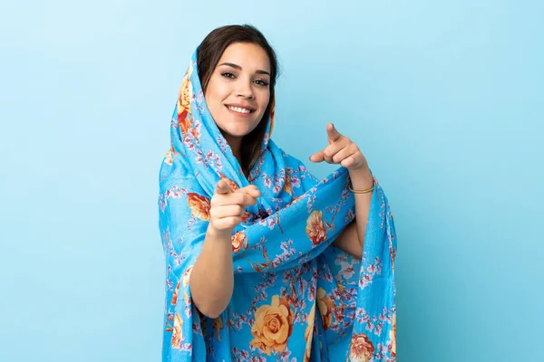 幸せな表情で前を指す青の背景に隔離された伝統的な衣装を持つ若いモロッコの女性 — ストック写真