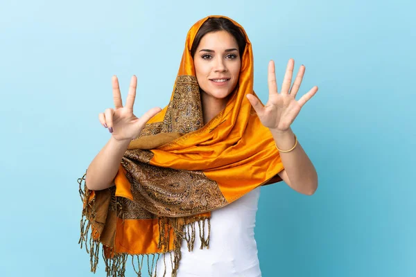 若いですモロッコの女性で伝統的な衣装は 指で8を数える青の背景に隔離 — ストック写真