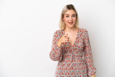 Beyaz arka planda izole edilmiş genç beyaz kadın şaşırmış ve ön tarafı işaret ediyor.