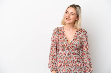 Beyaz arka planda izole edilmiş genç beyaz kadın yan bakıyor ve gülümsüyor.