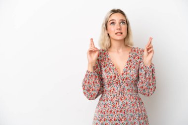 Beyaz arka planda izole edilmiş beyaz tenli genç bir kadın parmaklarını çapraz yapıp en iyisini diliyor.