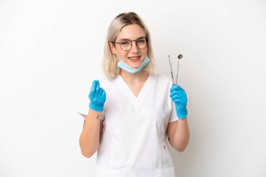 Beyaz arka planda izole edilmiş aletler taşıyan beyaz dişçi kadın para hareketi yapıyor.