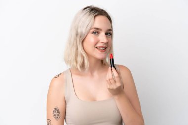 Beyaz arka planda kırmızı ruj tutan beyaz tenli genç bir kadın.