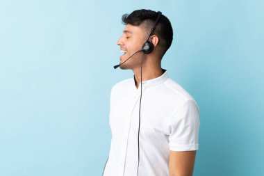 Tele pazarlamacı Kolombiyalı bir adam, izole bir arka planda çalışan bir kulaklıkla çalışıyor.