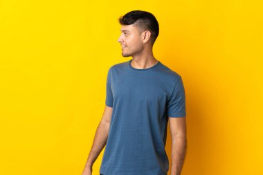 Sarı arka planda izole edilmiş genç Kolombiyalı adam.