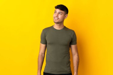 Genç Kolombiyalı bir adam sarı arka planda izole edilmiş.