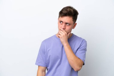 Genç, yakışıklı Brezilyalı bir adam beyaz arka planda izole edilmiş. Şüpheleri var ve kafası karışmış bir yüz ifadesi var.