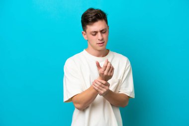 Genç ve yakışıklı Brezilyalı bir adam mavi arka planda izole edilmiş ellerindeki acıdan muzdarip