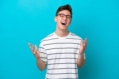 Genç ve yakışıklı Brezilyalı bir adam mavi arka planda izole edilmiş, gülümsüyor.