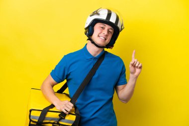 Sırt çantalı genç Brezilyalı adam sarı arka planda izole edilmiş ve parmağını kaldırıyor.