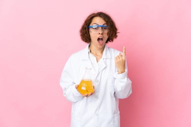 Pembe arka planda izole edilmiş genç İngiliz bilim kadını parmağını kaldırarak çözümü bulmaya çalışıyor.