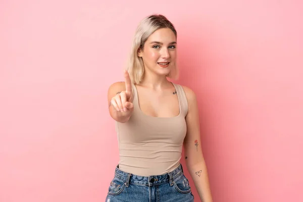 ピンクの背景に孤立した若い白人女性が指を見せて持ち上げる — ストック写真