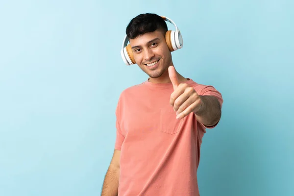 Jonge Colombiaanse Man Geïsoleerd Blauwe Achtergrond Luisteren Muziek Met Duim — Stockfoto