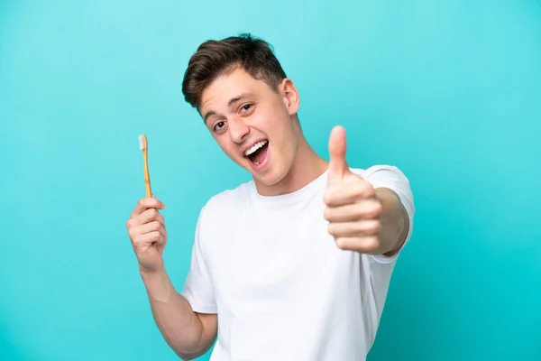 巴西年轻人用大拇指在蓝色背景下刷牙 因为发生了件好事 — 图库照片