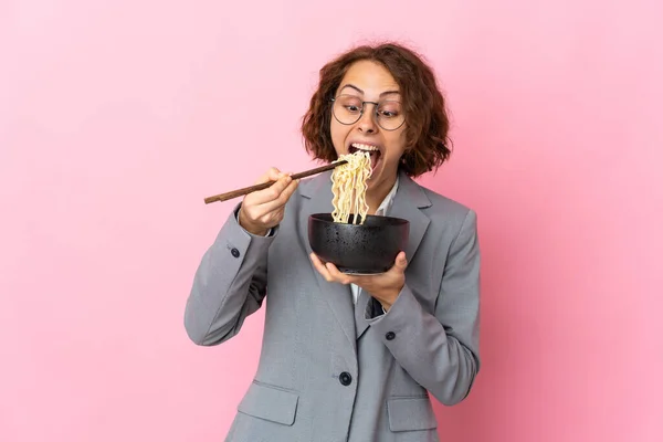 ピンクを背景に箸で麺を握り食べながら孤立した若いイギリス人女性 — ストック写真