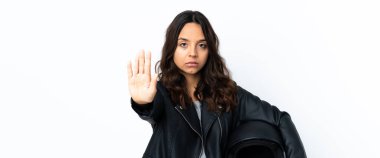 Beyaz arka planda motosiklet kaskı tutan genç bir kadın dur hareketi yapıyor ve hayal kırıklığına uğruyor.