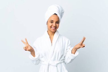 Young woman in bathrobe over isolated white background showing victory sign with both hands