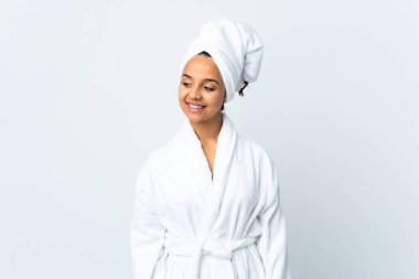 Bornozlu genç bir kadın soyutlanmış beyaz arka planda yan tarafa bakıyor ve gülümsüyor.