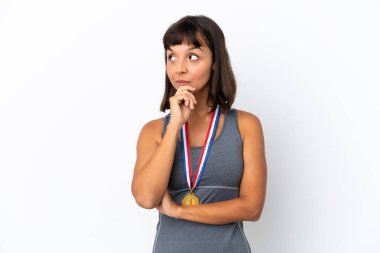 Young mixed race woman with medals isolated on white background having doubts and with confuse face expression