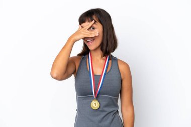 Young mixed race woman with medals isolated on white background covering eyes by hands and smiling