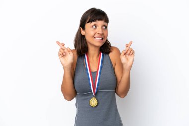 Young mixed race woman with medals isolated on white background with fingers crossing