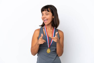 Young mixed race woman with medals isolated on white background pointing to the front and smiling