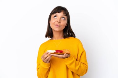 Young mixed race woman holding sashimi isolated on white background and looking up