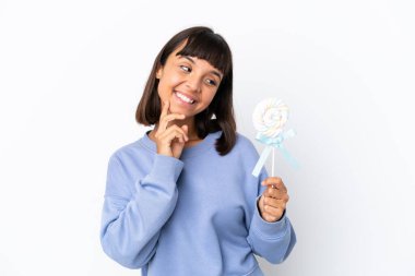 Young mixed race woman holding a lollipop isolated on white background thinking an idea while looking up