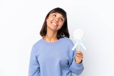 Young mixed race woman holding a lollipop isolated on white background thinking an idea while looking up